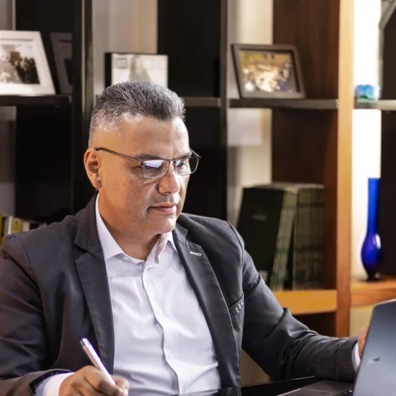 Miguel Quintero revisando laptop con lentes